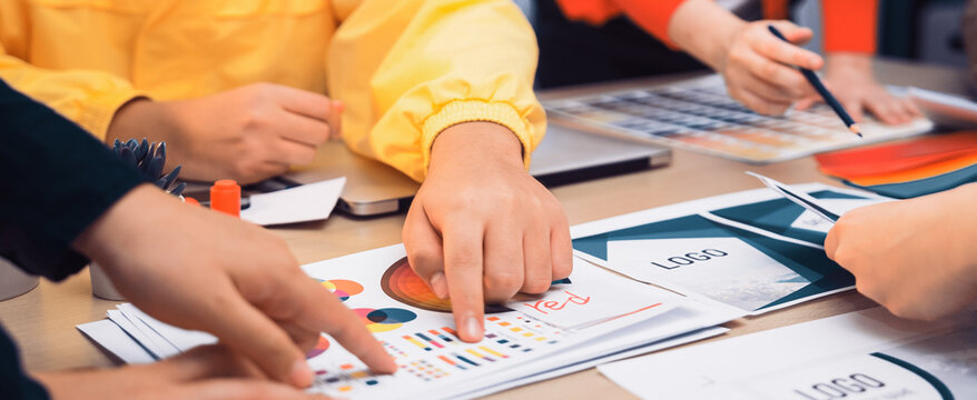 A dynamic team engages in a creative brainstorming session, collaborating on design concepts and analyzing colorful charts and drafts on a modern workspace. SACTR