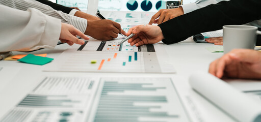 A diverse team of professionals engages in a collaborative meeting, analyzing financial reports and data charts in a modern office space, fostering innovative solutions. SACTR