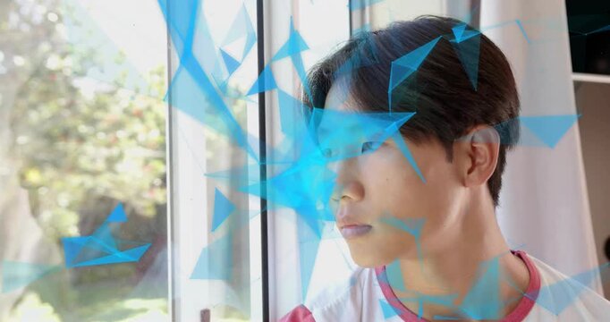 Teenage boy following blue polygon graphics sweeping across window, shifting head for motion design