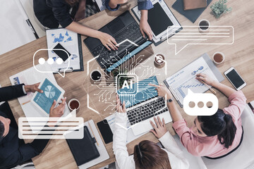A high-angle view of a diverse business team collaborating over a laptop. Digital icons represent artificial intelligence and communication, enhancing teamwork and productivity. Gantry