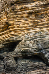 layered coastal rock formations showing rich textures, colors, and erosion patterns, highlighting geological strata shaped by natural forces over time