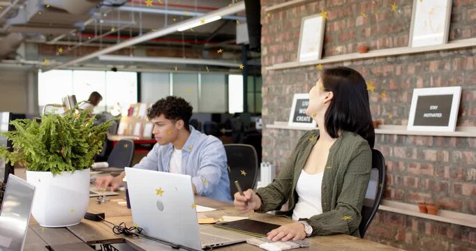 Designer tapping pen and launching animated UI to review design in open office as colleague nears