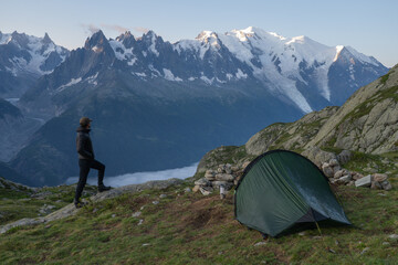 Hiker standing by tent viewing Mont Blanc massif and Bossons Glacier, France © R
