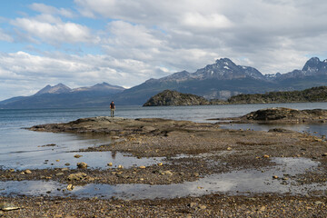 Hiker standing on rocky outcrop in vast Beagle Channel, Tierra del Fuego