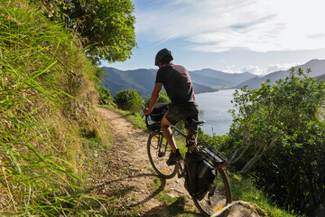 Cyclist bikepacking coastal Queen Charlotte Track in Marlborough Sounds, NZ © R