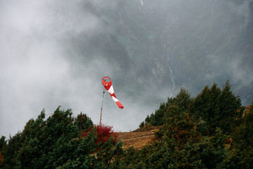 Wind indicator stands on a mountain ridge surrounded by mist in the early morning hours