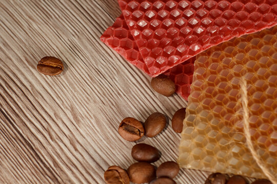 Close up of a beeswax candle with red honeycomb sheet and coffee beans on a wooden background - Powered by Adobe