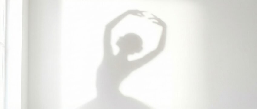 Shadow of a woman dancer on a white wall. Graceful ballerina silhouette performing, artistic movement concept for studio wall art. Banner with copy space