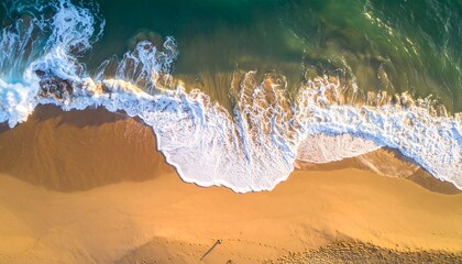 Aerial view of ocean waves meeting a sandy beach with a lone figure walking below