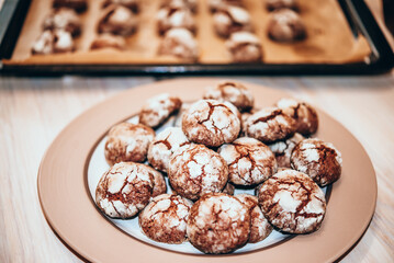 Freshly baked Chocolate crinkle cookies stacked on brown ceramic plate