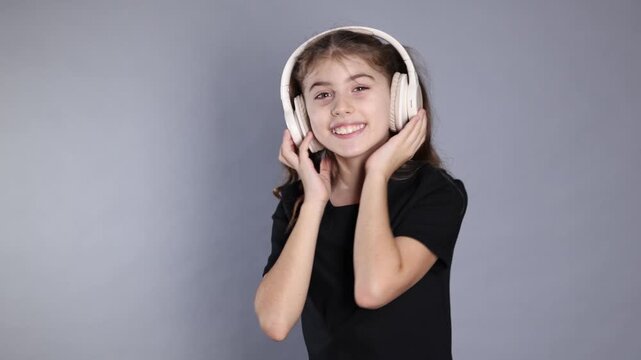 Smiling girl in headphones listening music on grey background