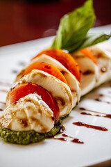Caprese salad served on a white plate with a garnish at a high end Italian restaurant 
