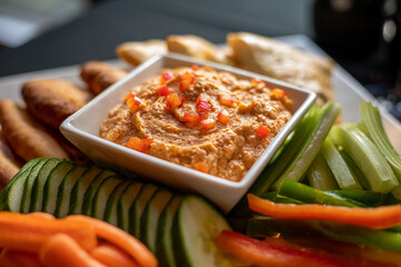 Roasted red pepper hummus served with pita bread cucumbers carrots at a high end wine bar and restaurant