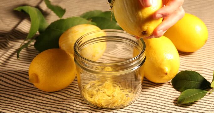 Woman zesting lemon into jar at table, closeup