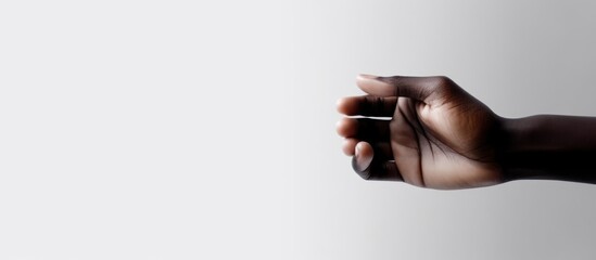 Naklejka premium Close-up of a dark-skinned hand holding something against a gradient background.