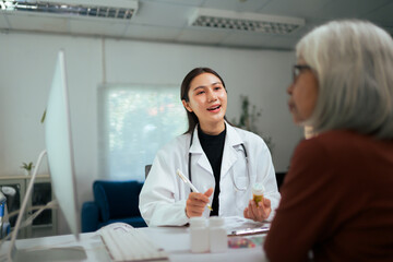 Fototapeta premium Asian doctor consulting elderly patient about medication