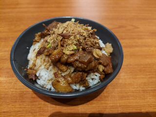 Savory braised pork cubes served over warm white rice, topped with crispy fried shallots for a rich and flavorful comfort dish.