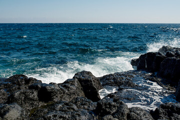Dynamic waves crashing against the rocks on Jeju Island, showcasing the islands wild beauty and coastal charm