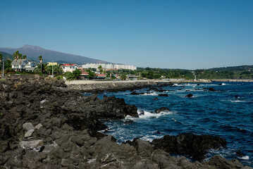 Scenic view of Jeju Islands coastline, featuring rocky shores and clear blue skies Perfect for nature lovers and travel enthusiasts