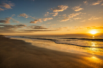 Obraz premium Sunrise over the ocean with waves and sandy beach in the morning sky