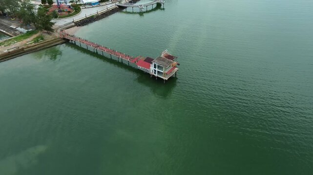 Aerial perspective showing a quiet beach restaurant stretching out into the calm green waters of Batam