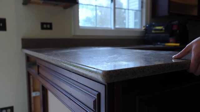Contractor removes old kitchen countertop during a home renovation project. The worker lifts and detaches the laminate counter, preparing for new installation.