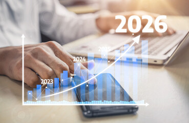 A business professional analyzes future growth trends using a smartphone and laptop. The graphic...
