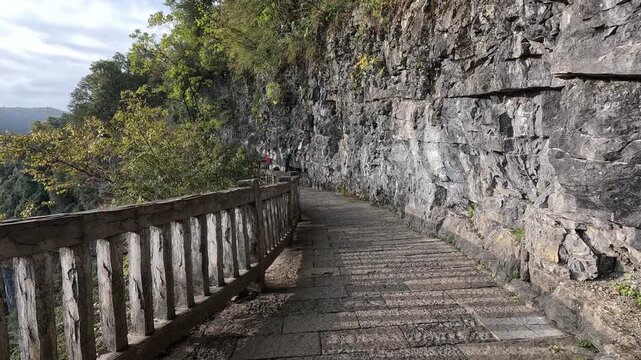 Walking path along the cliff in Wulong National Geological Park in Chongqing, China. The Three Natural Bridges hiking trail in Wulong Karst National Geology Park features numerous stairs and uneven te