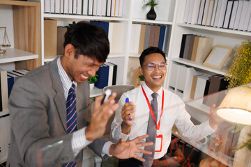 Two male employees in suits are designing a business plan, discussing various plans in their office, and one is drawing on a whiteboard. The scene looks cheerful and fun.

