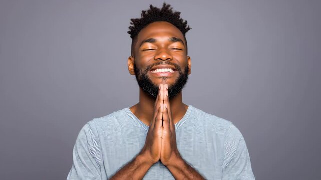 Grateful man thinking person male with hands together prayer pose calm serene expression beard casual shirt studio portrait gray background peaceful mood hopeful look gentle smile calm meditation