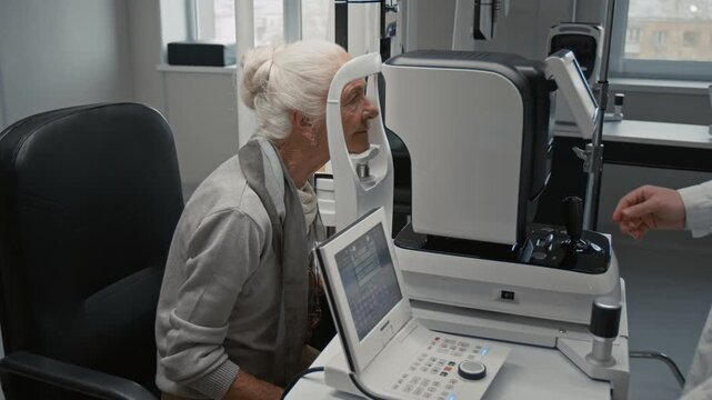 Medium shot of senior woman during eye exam in ophthalmologist office at clinic putting head into frame of modern diagnostic machine, copy space