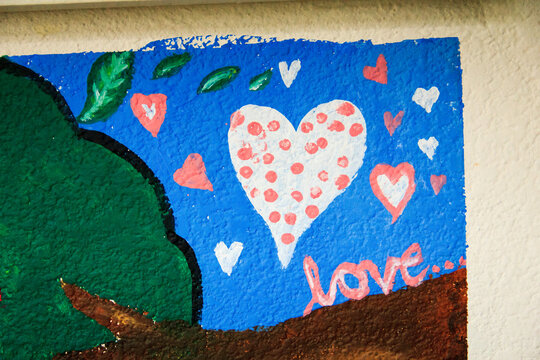 A mural with white heart with red dots, surrounded by hearts and green leaves, with “love...” text on blue background. - Powered by Adobe