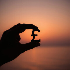 Financial Stability & Growth High-Resolution Professional  of a Hand Holding the British Pound Sterling Symbol at Dawn