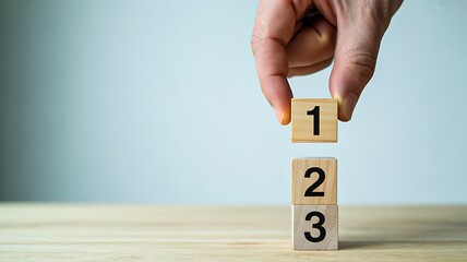 Hand stacking wooden blocks with numbers representing step by step progress
