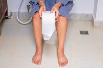 Woman sitting on the toilet bowl in the bathroom. She has stomach ache. Poor digestive system....