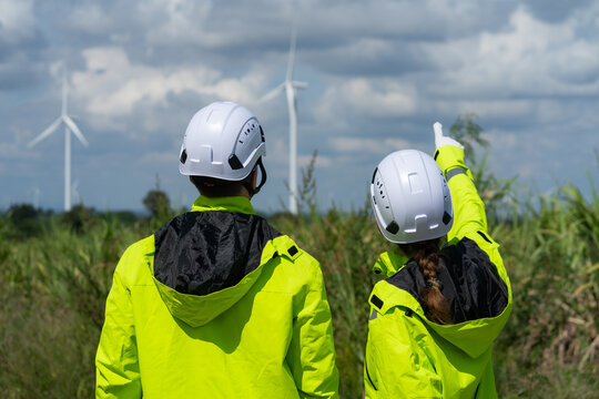Renewable energy engineers review wind farm project plans and data to analyze the efficiency and safety of wind power generation systems. - Powered by Adobe
