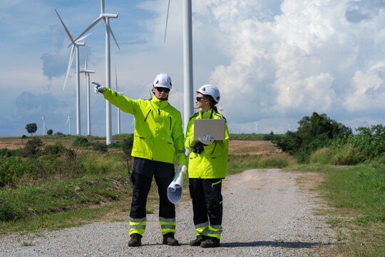 Renewable energy engineers review wind farm project plans and data to analyze the efficiency and safety of wind power generation systems. - Powered by Adobe