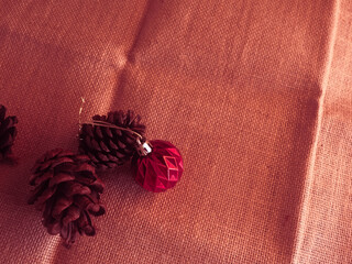 A red Christmas ball resting on brown sackcloth with a soft pink tone at night creates a warm and festive holiday ambiance.