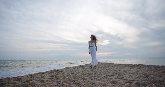 Enjoy a peaceful beach walk at sunset with gentle waves and a serene atmosphere as the sky changes colors