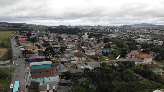 rone view over a small town with colorful houses, narrow streets, and surrounding fields under cloudy skies in southern Brazil