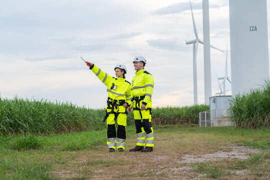 Renewable energy engineers review wind farm project plans and data to analyze the efficiency and safety of wind power generation systems. - Powered by Adobe