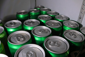 Close up top view of many green aluminum beverage cans in storage. This abundant group of unopened soda or drink containers shows large supply of cold refreshment