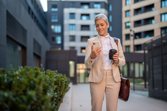 Businesswoman checking smartphone connecting with urban environment - Powered by Adobe