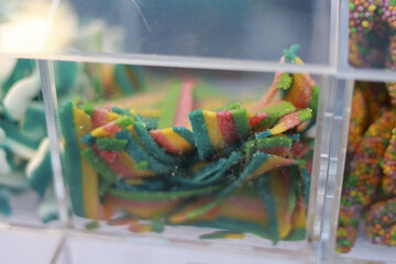Tempting and delicious close up of colorful rainbow candy strips. This chewy and sweet confectionary in clear container at sweetshop, fun and tasty treat
