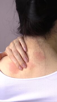 【縦型動画】首や背中を掻く若い女性の後ろ姿