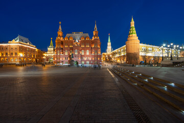 Fototapeta premium Moscow, Russia. Manezhnaya Square. Evening view of the building of the State Historical Museum and the towers of the Moscow Kremlin. Blurred figures of people in long exposure.