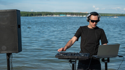 Caucasian man works as a DJ on the beach. 