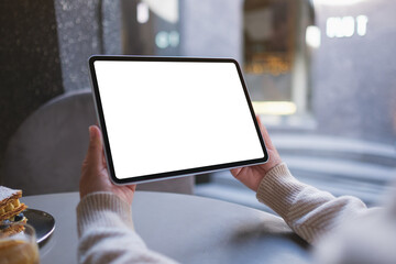 Mockup image of a woman holding digital tablet with blank white desktop screen in cafe