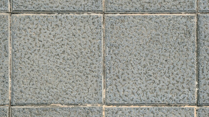 Textured concrete paving tiles for outdoor, patio, sidewalk and garden. Square slabs made of mixture of cement, sand, gravel and anti-slip, resistant and durable material. Public floor texture. 