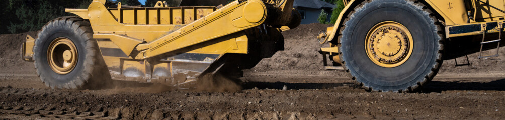 Wheel Tractor Scraper moving mineral dirt and working on groundwork for new housing development...